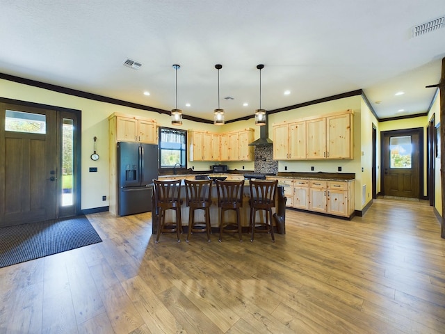 kitchen with light brown cabinets, black refrigerator with ice dispenser, and a healthy amount of sunlight