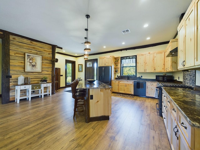 kitchen featuring decorative light fixtures, a kitchen island, a wealth of natural light, and black appliances