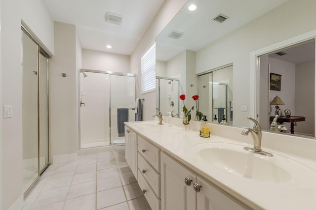 bathroom featuring tile patterned flooring, vanity, toilet, and a shower with door