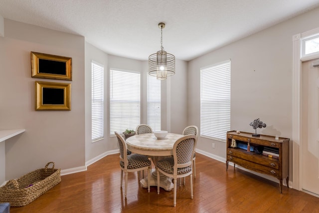 dining room featuring hardwood / wood-style floors, a textured ceiling, and an inviting chandelier