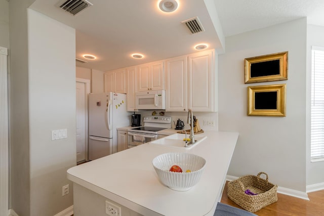 kitchen with a wealth of natural light, sink, light hardwood / wood-style floors, and white appliances