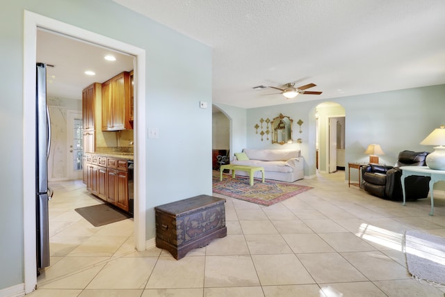 tiled bedroom featuring stainless steel fridge, a textured ceiling, ensuite bathroom, and ceiling fan