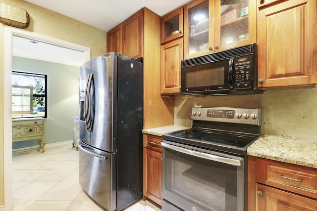 kitchen with light stone counters, light tile patterned floors, and appliances with stainless steel finishes