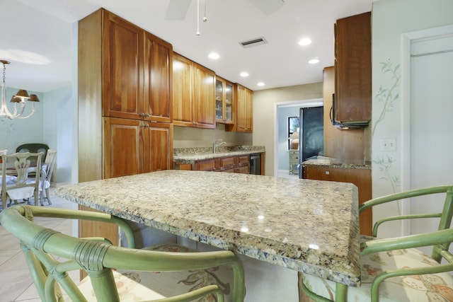 kitchen with pendant lighting, a kitchen breakfast bar, sink, light stone countertops, and light tile patterned floors