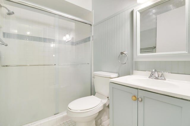 bathroom with tile patterned floors, vanity, toilet, and a shower with door