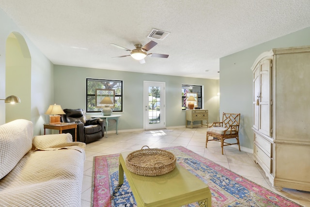 living room with ceiling fan, light tile patterned floors, and a textured ceiling