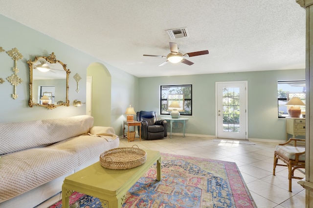 living room with ceiling fan, light tile patterned floors, and a textured ceiling