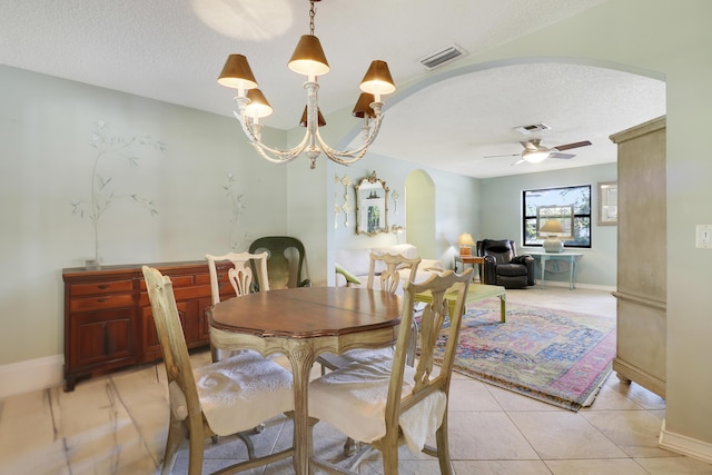 dining area with ceiling fan with notable chandelier, light tile patterned flooring, and a textured ceiling