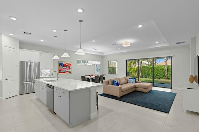 kitchen with pendant lighting, white cabinets, an island with sink, tasteful backsplash, and stainless steel appliances