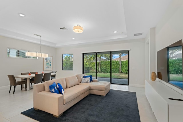 living room featuring light tile patterned floors and a tray ceiling