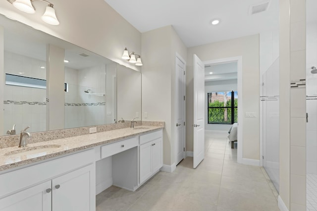 bathroom with tiled shower, vanity, and tile patterned flooring