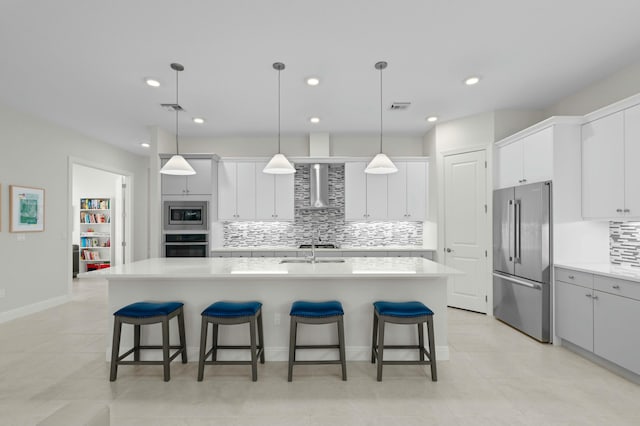 kitchen with a center island with sink, hanging light fixtures, and appliances with stainless steel finishes