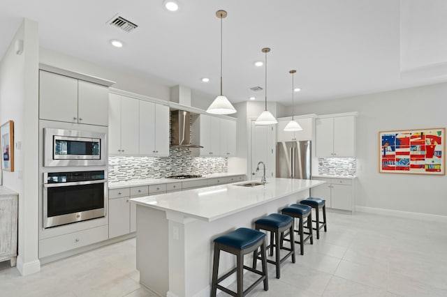 kitchen with appliances with stainless steel finishes, sink, decorative light fixtures, a center island with sink, and white cabinetry