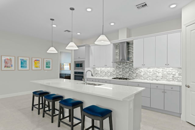 kitchen featuring decorative light fixtures, sink, stainless steel appliances, and an island with sink