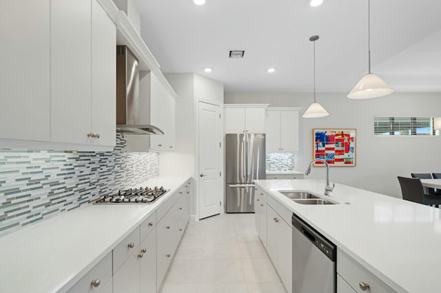 kitchen featuring white cabinetry, sink, wall chimney exhaust hood, hanging light fixtures, and stainless steel appliances