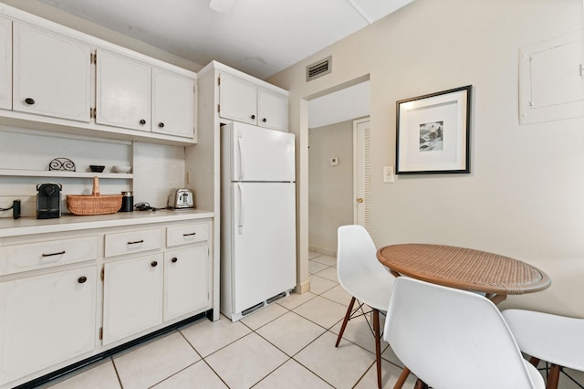 kitchen featuring white cabinets, light tile patterned flooring, and white refrigerator