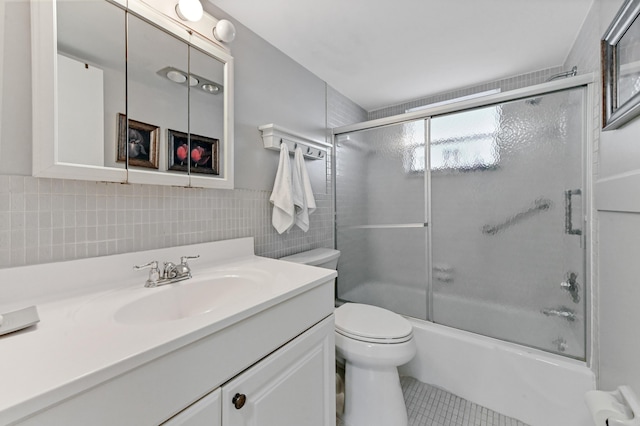 full bathroom featuring vanity, tile patterned floors, bath / shower combo with glass door, toilet, and tile walls