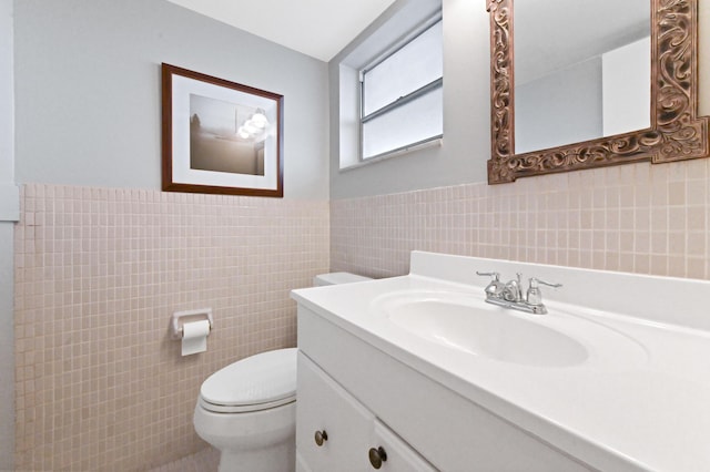 bathroom featuring vanity, toilet, and tile walls