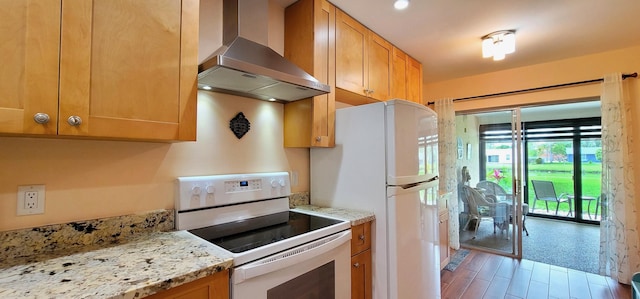 kitchen with light stone countertops, white appliances, and wall chimney range hood