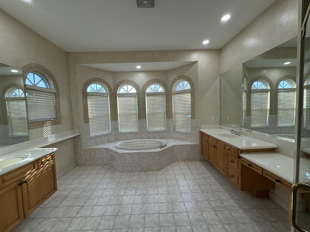 bathroom featuring plenty of natural light, vanity, and tiled bath