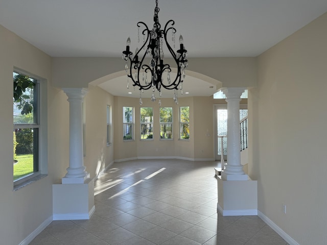 unfurnished dining area featuring a chandelier, light tile patterned floors, decorative columns, and a healthy amount of sunlight