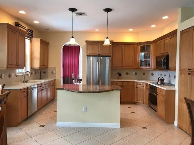 kitchen featuring appliances with stainless steel finishes, tasteful backsplash, sink, decorative light fixtures, and a center island