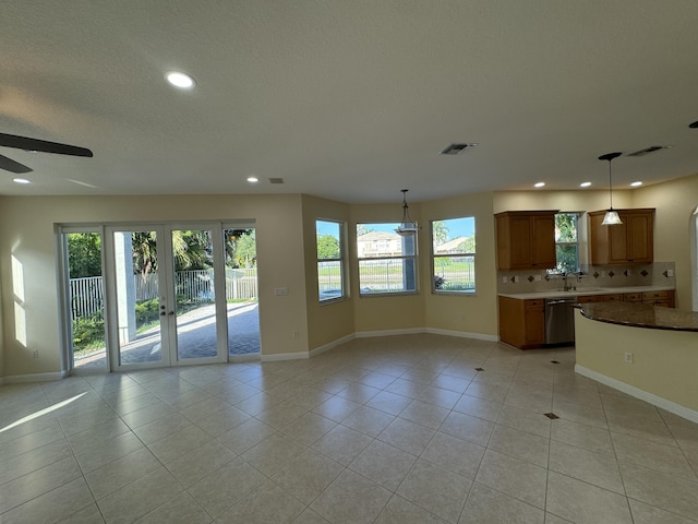 unfurnished living room with ceiling fan, french doors, sink, a textured ceiling, and light tile patterned floors