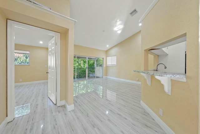 interior space with a wealth of natural light, vaulted ceiling, and light wood-type flooring