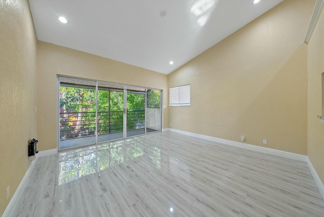 unfurnished room with heating unit, light hardwood / wood-style floors, high vaulted ceiling, and a wealth of natural light