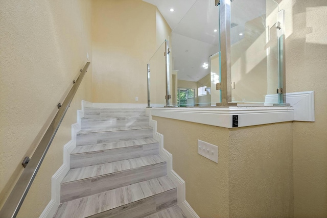 staircase featuring wood-type flooring and vaulted ceiling