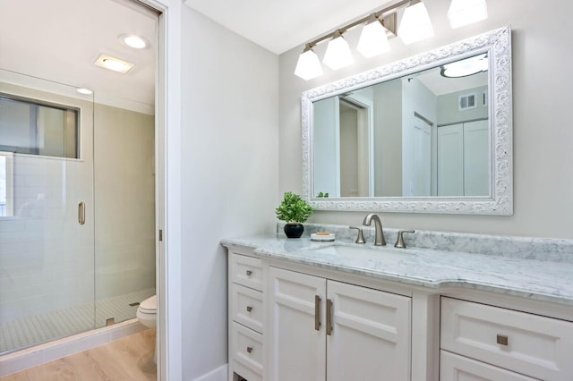 bathroom with toilet, vanity, an enclosed shower, and hardwood / wood-style flooring