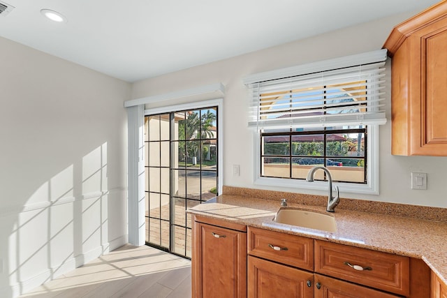 kitchen featuring light stone countertops, sink, and light hardwood / wood-style floors