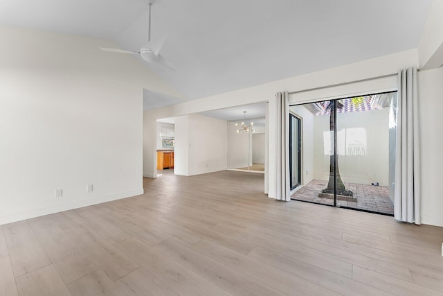 spare room featuring ceiling fan with notable chandelier, light hardwood / wood-style floors, and vaulted ceiling