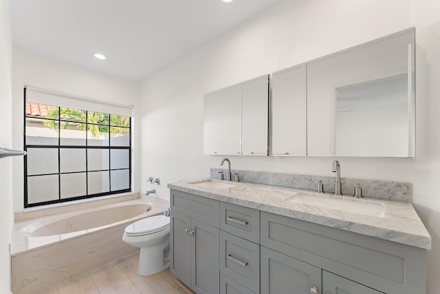 bathroom featuring a washtub, vanity, and toilet