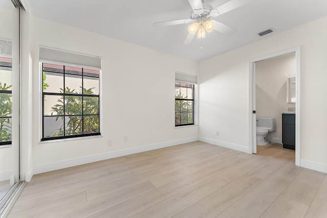 unfurnished bedroom with light hardwood / wood-style floors, ensuite bath, multiple windows, and ceiling fan