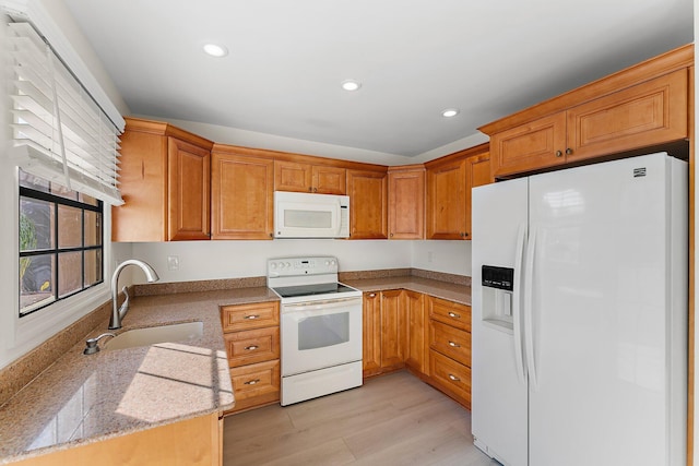 kitchen with light stone counters, white appliances, sink, and light hardwood / wood-style flooring