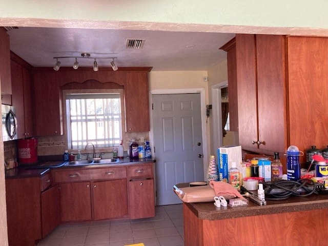 kitchen featuring backsplash, kitchen peninsula, sink, and light tile patterned floors