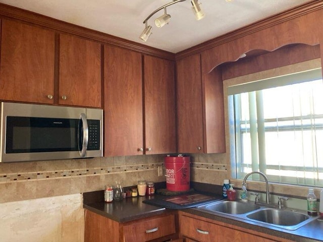 kitchen featuring rail lighting, sink, and tasteful backsplash