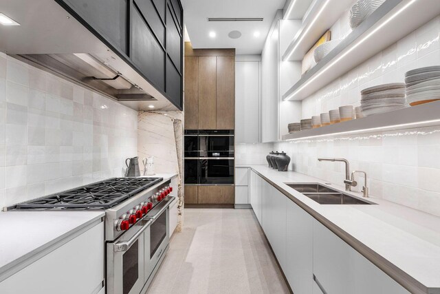 kitchen featuring white cabinets, double oven range, sink, and tasteful backsplash