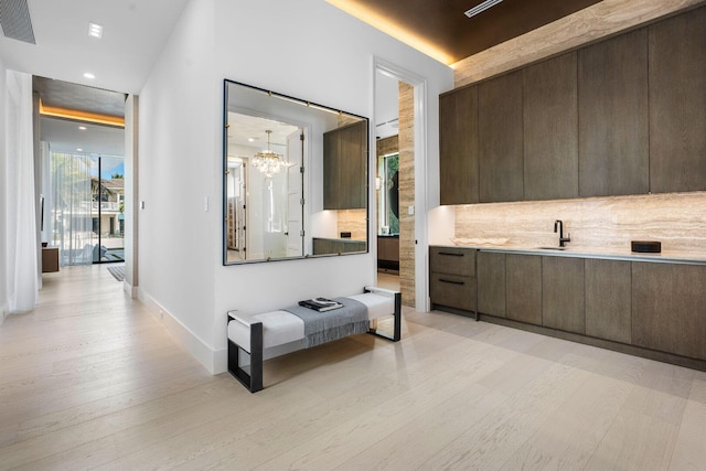 corridor featuring a notable chandelier, sink, and light wood-type flooring