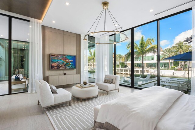 bedroom featuring access to exterior, a wall of windows, light wood-type flooring, and a chandelier