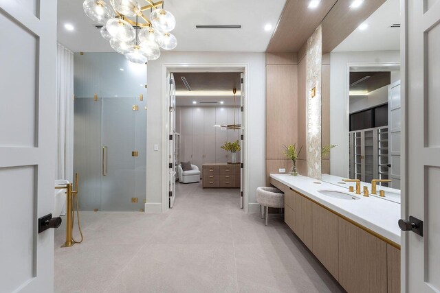 bathroom with a chandelier, vanity, and a shower with door