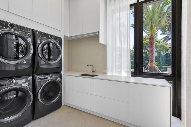 laundry room with sink, light tile patterned floors, stacked washing maching and dryer, and plenty of natural light