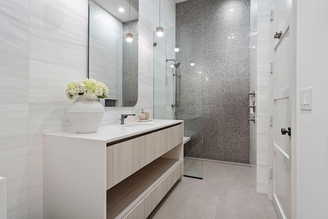 bathroom featuring vanity, tiled shower, tile walls, and tile patterned floors