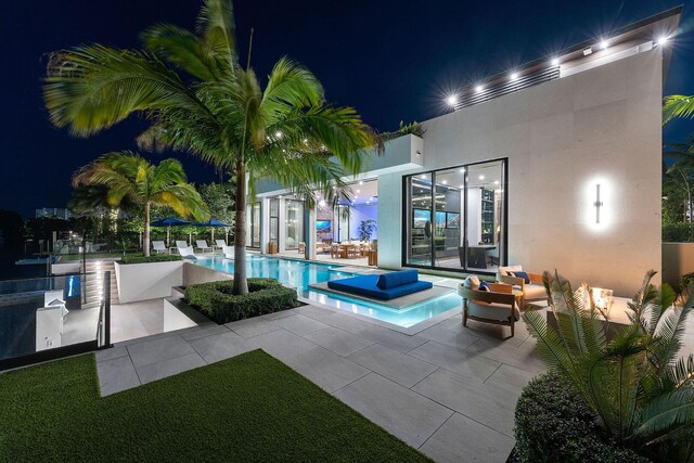 pool at twilight with a patio area