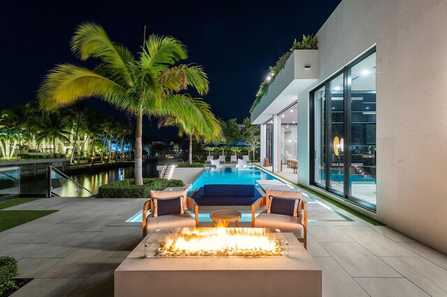 pool at twilight with a patio area and an outdoor fire pit