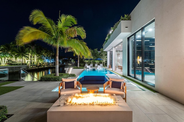 patio at night with a water view and a fire pit