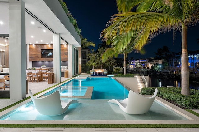 pool at night featuring a patio