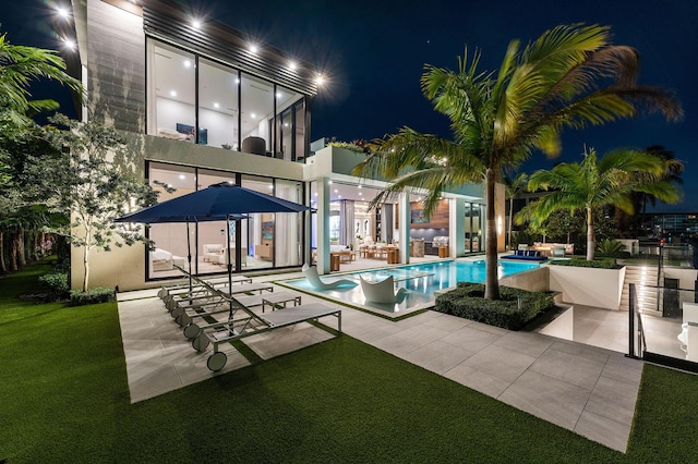 back house at twilight with a patio and a lawn