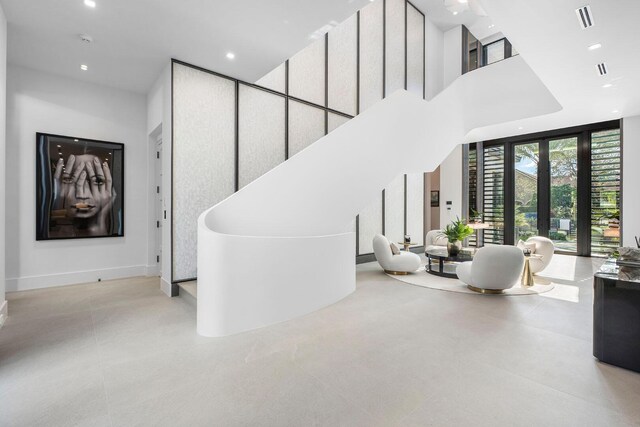 staircase with floor to ceiling windows, a towering ceiling, and french doors